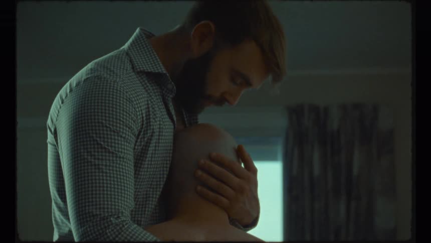 A man hugs his partner and kisses him on the head