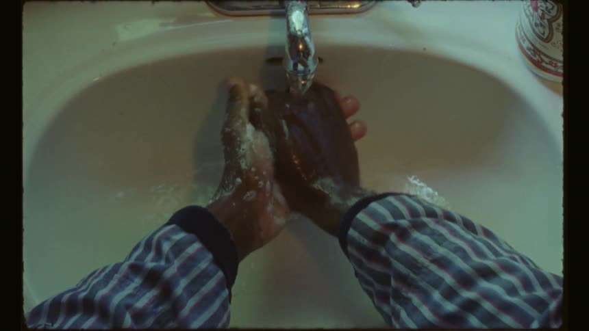 A black man is washing his hands in a sink