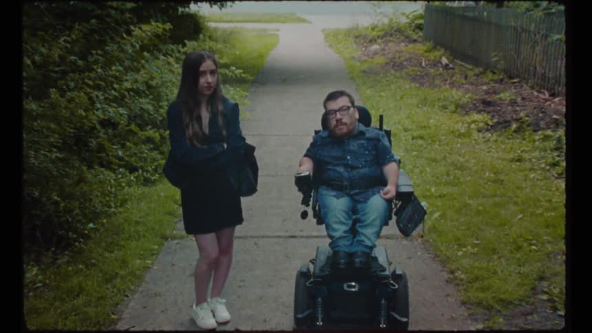 Vintage footage of a worried looking girl standing next to a man in a wheelchair in a neighborhood