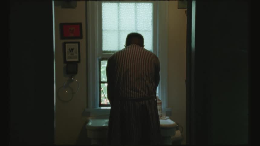 Man stands in front of sink place near window in bathroom and washes his hands