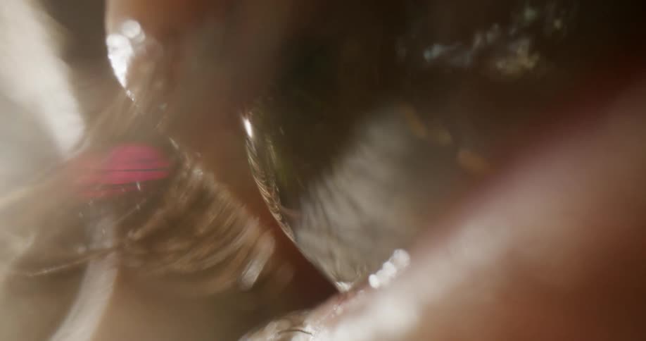 Extreme close up of the moving humid eye of a woman with long eyelashes looking up