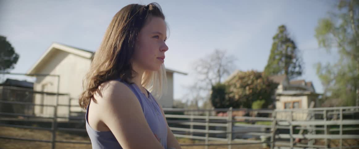 A woman walks across her ranch with her arms crossed