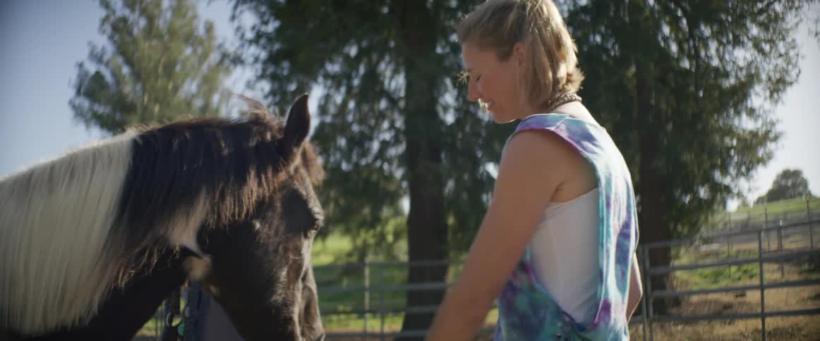 A woman and her daughter pet a horse in a pasture