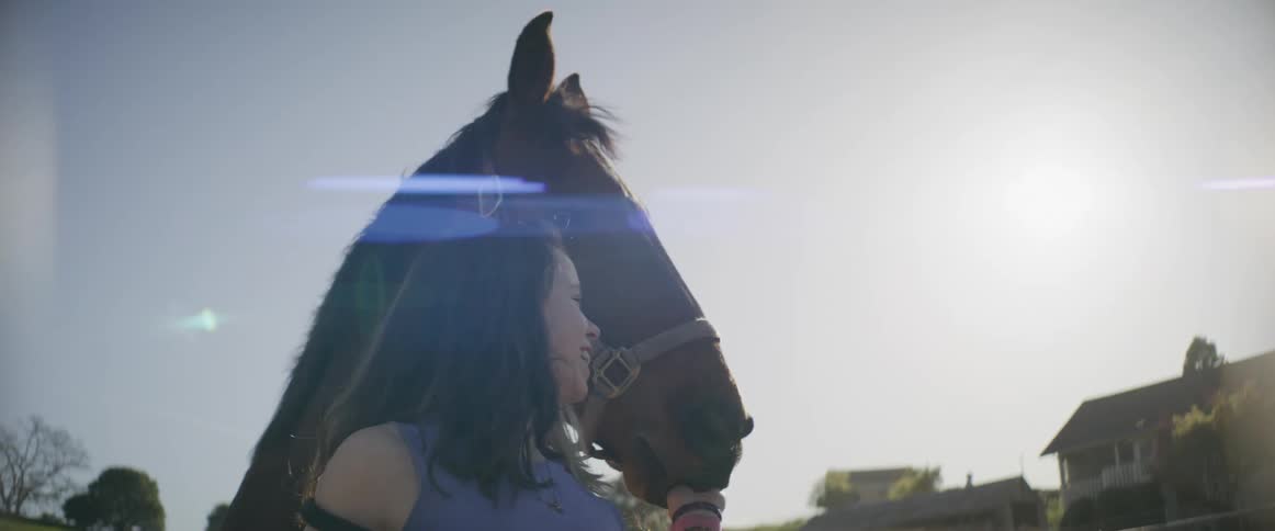 A woman smiles while petting her horse