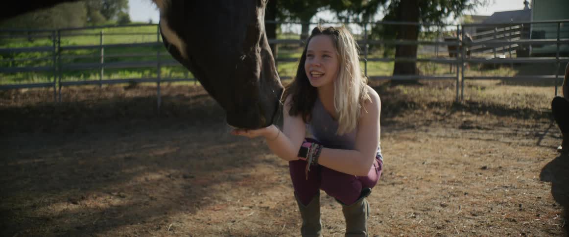 Young girl feeding horse from palm of her hands at a ranch in the country