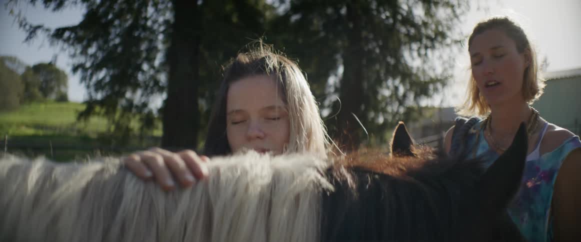 A teenager is petting her horse