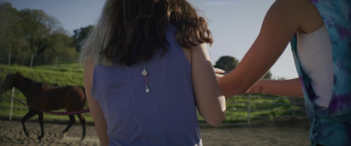 A girl leads a horse around on a leash