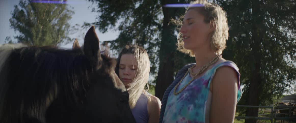 A woman and her daughter stand with their eyes closed as they stand next to a horse