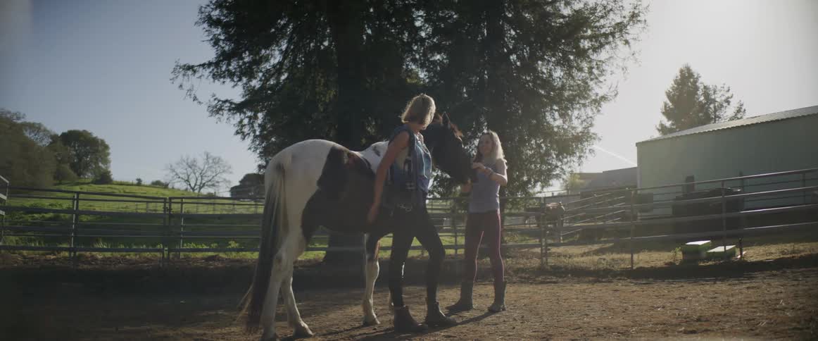 The woman and girl are petting a horse