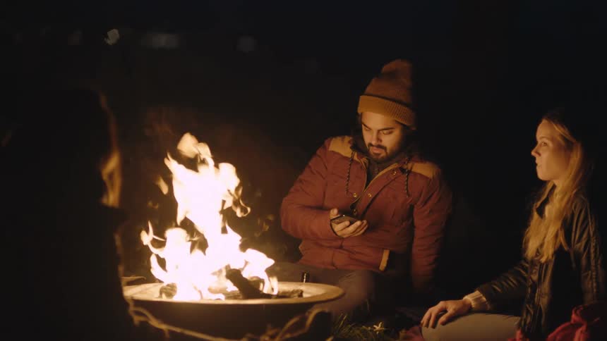 Friends sitting near a campfire at night