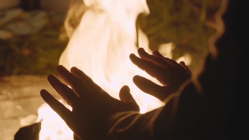 A person warming their hands by a bonfire