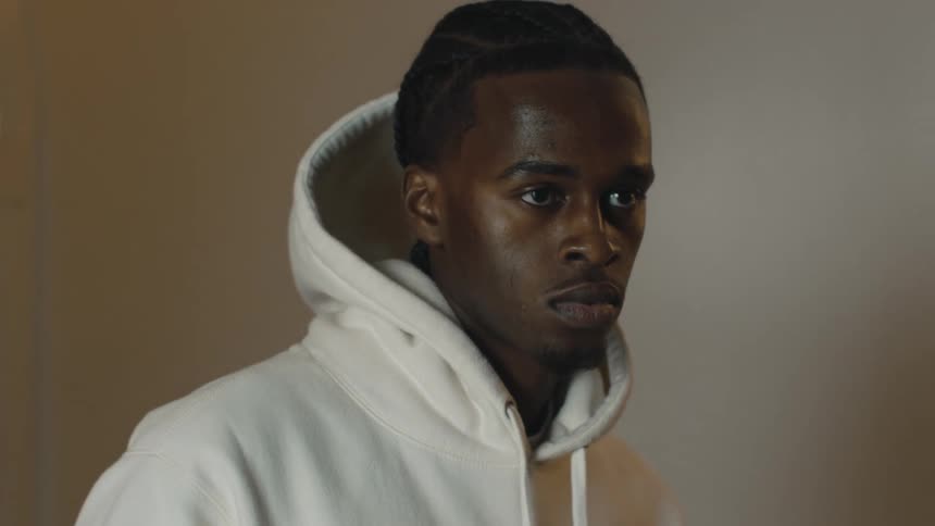 Man wearing a hoodie speaks to another before they walk away in different directions