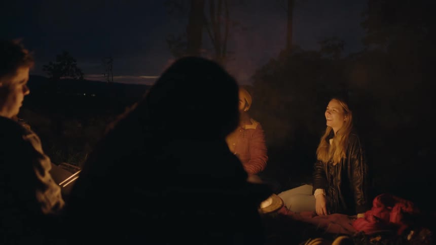 Friends hanging out around a bonfire at night