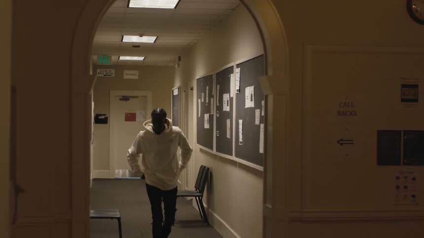 A man chases a teenager down the hall