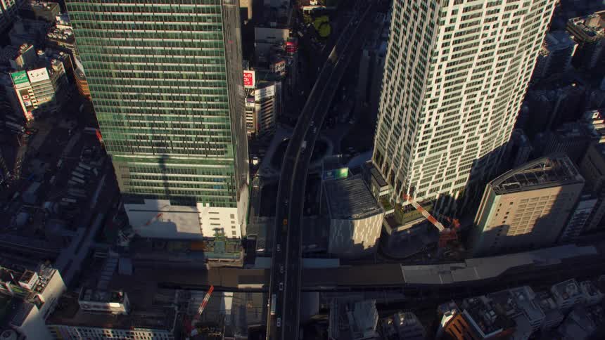 Cars are traveling on a highway in between buildings and skyscrapers in a city