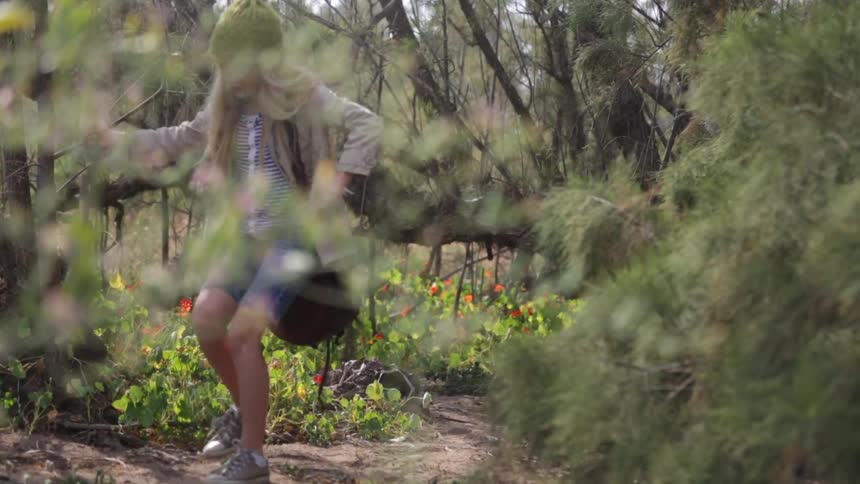 A girl hikes through the wilderness then sits down and opens her bag