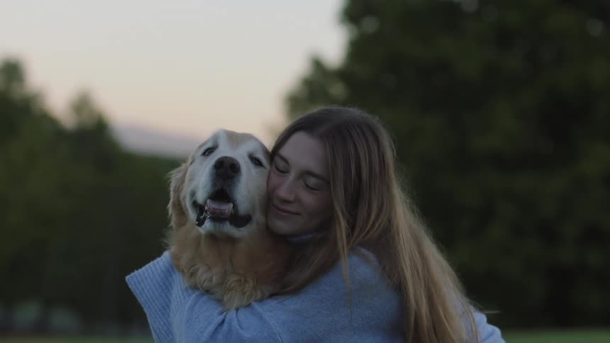 A woman hugging her dog outdoors in spring