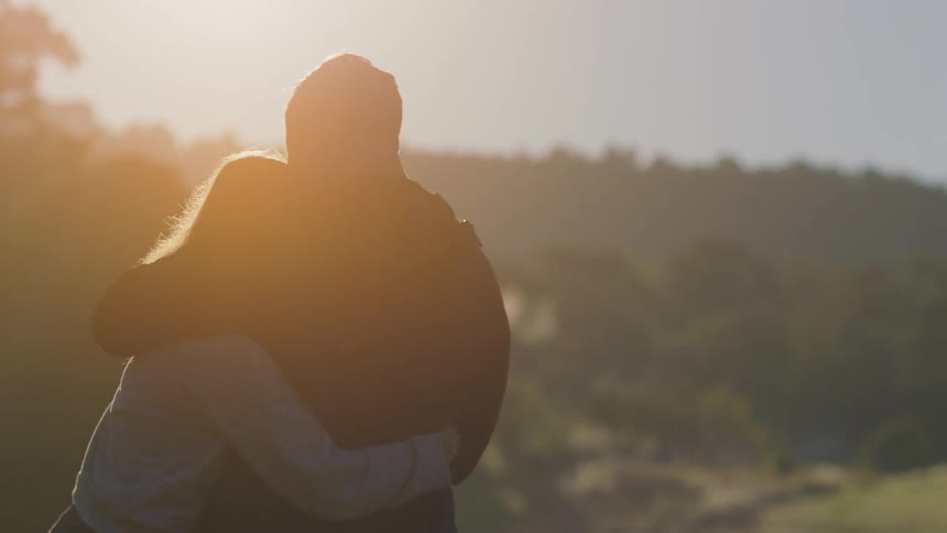 A man and woman hugging outside on a sunny morning