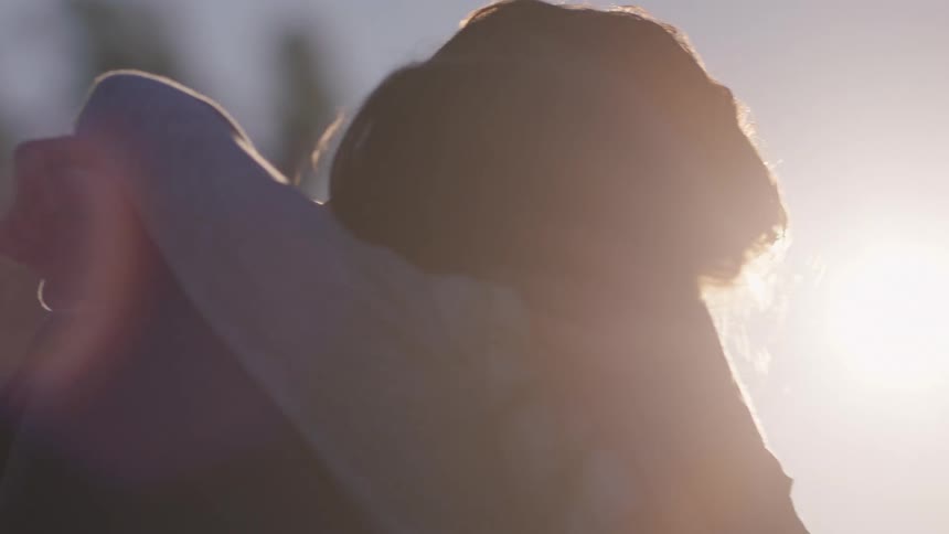 A woman smiles and hugs her boyfriend in a golden field