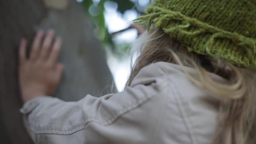 A girl is carving into a tree trunk then looks back