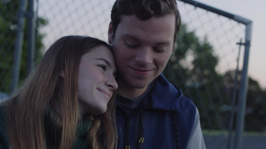 A couple are leaning against each other outside