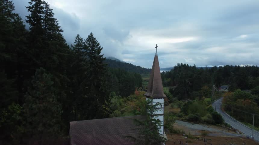 Trees and hills surround st anns catholic church and cemetery on vancouver island