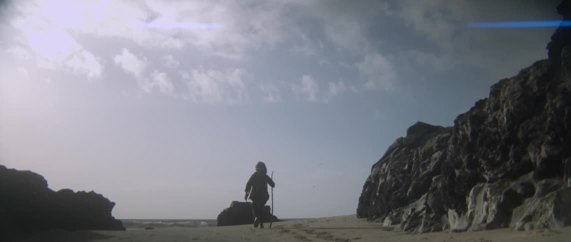 A child hikes on the beach with a walking stick