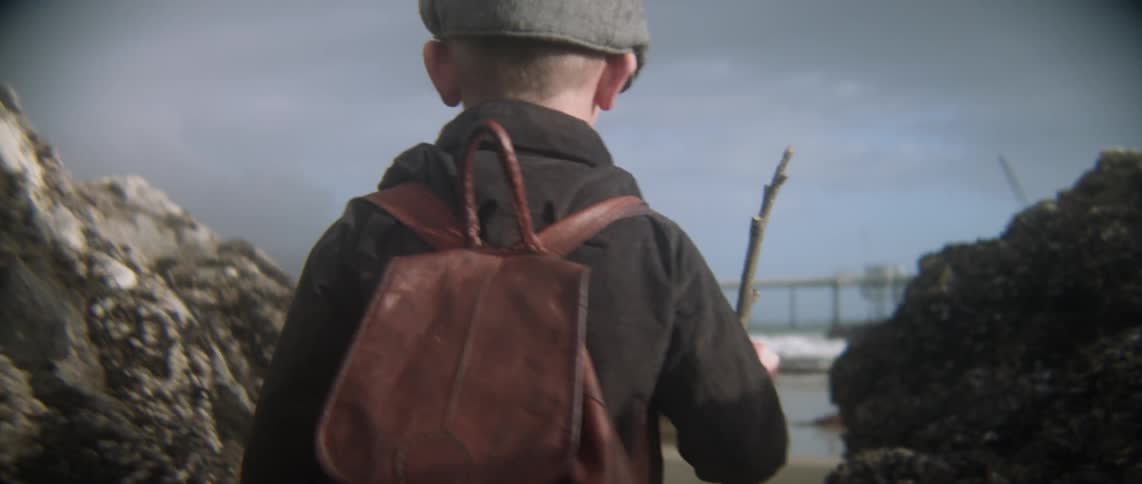 A child walks through rocks towards the beach