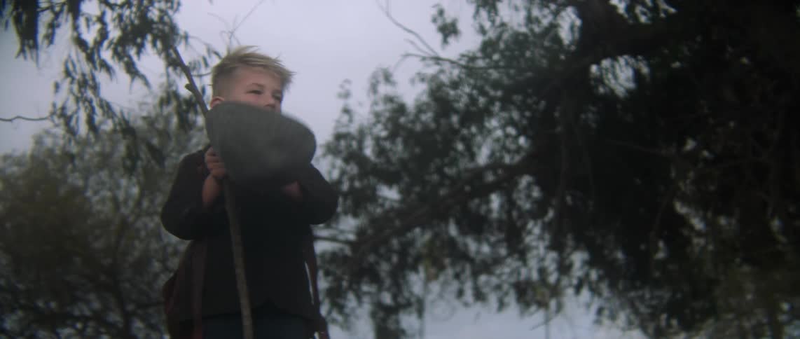 A boy removes his hat scratches head and puts it back on