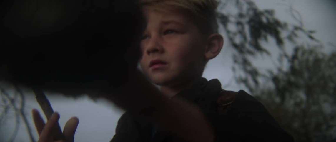 A young boy removes his hat, scratches his head and puts his hat back on