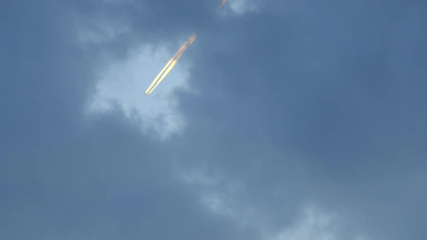 View of a skyline with many clouds and a plane passing by leaving a trail