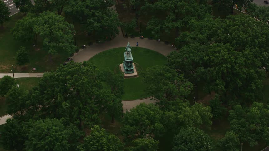 A large statue in a park in the center of a roundabout in a city during the day