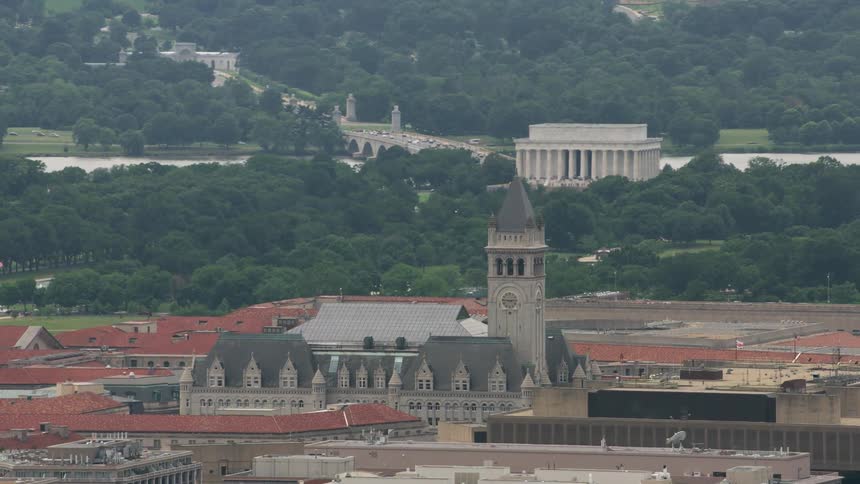 Cathedral with clock tower stands in center of campus with landmark with classical architecture and busy bridge over the river in the background
