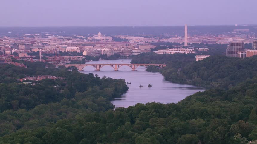 A bridge spanning a river through a metropolis in the evening