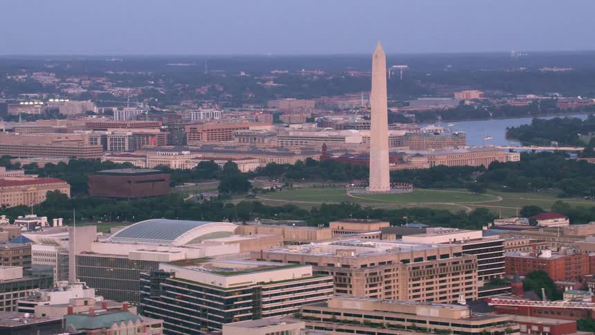 A tall monument looms over a city during the day