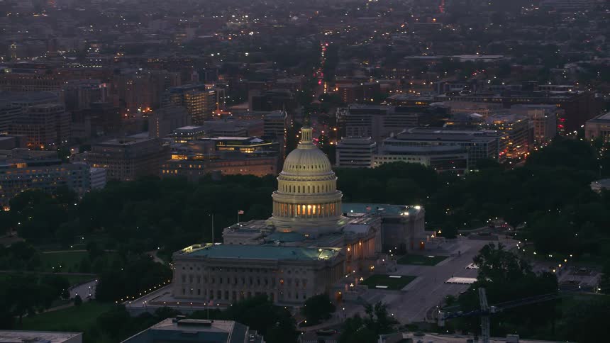 The us capitol building dome glowing at night above the dc streets