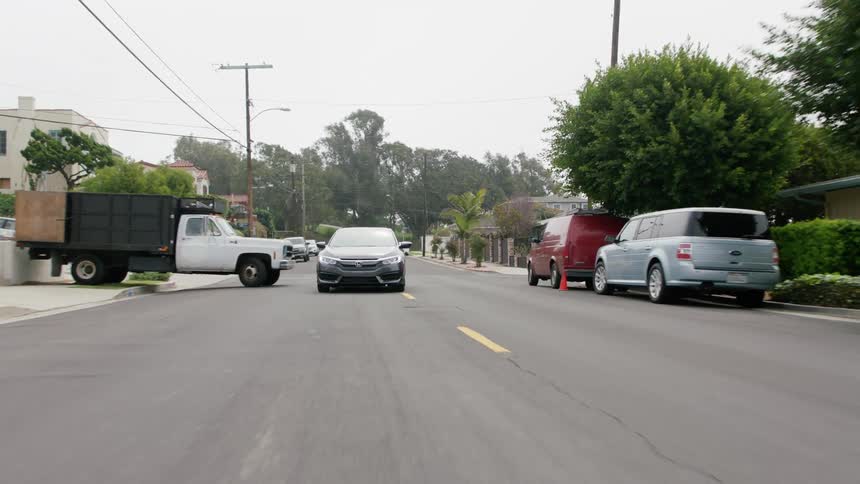 A vehicle drives down a neighborhood street