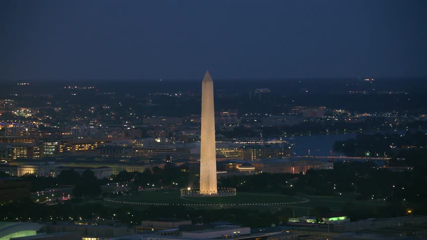 The washington monument is lit up at night in the city of washington dc