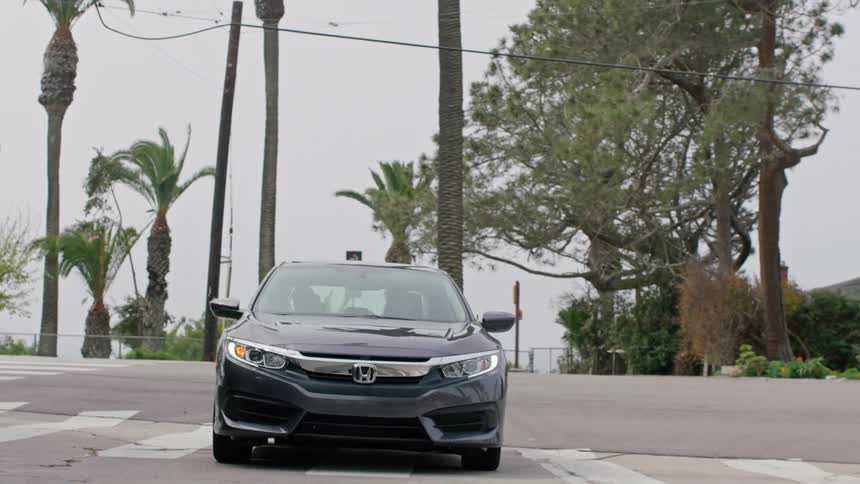 A car is driving through a suburban city during the spring time