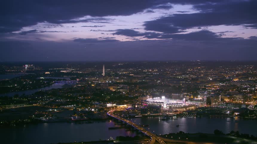 Stadium lights shine brightly near river winding through city