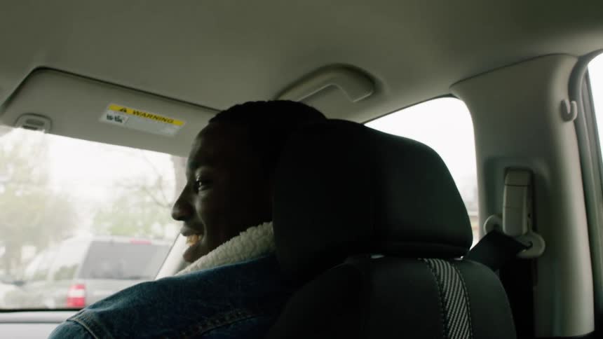 A man is a passenger in a car driving through a neighborhood