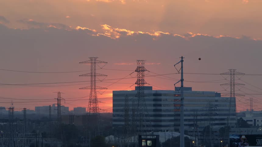 Power lines are in front of a building at sunset