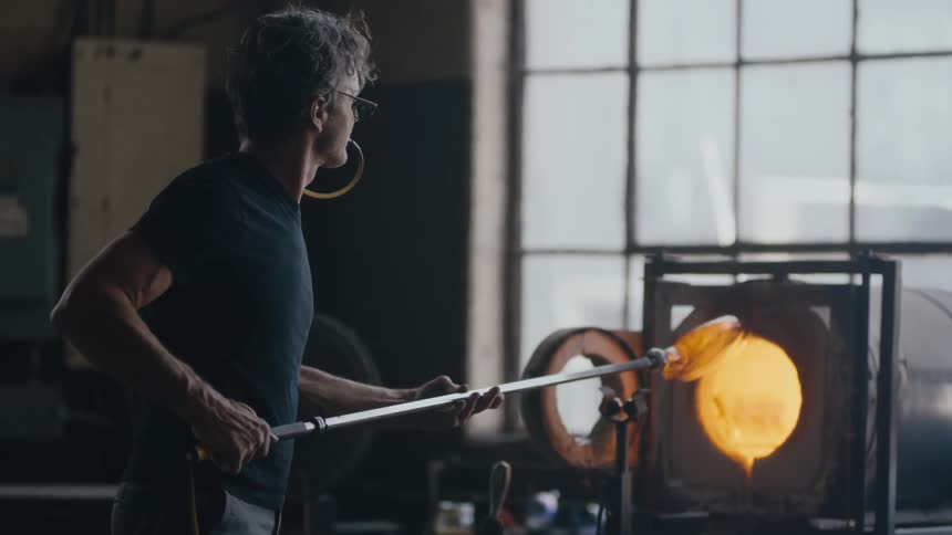 Glass maker pulls glass from hot furnace
