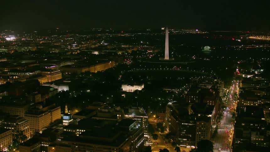 A tall monument looms over a metropolis at night
