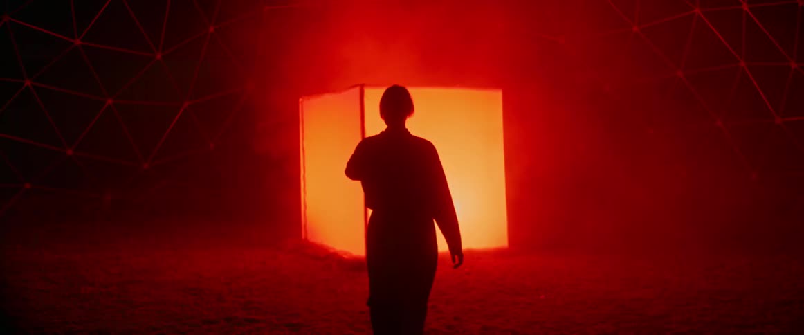 A woman walks towards the large glowing cube