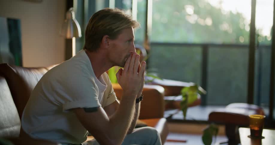 A man is sitting on his couch and watching television