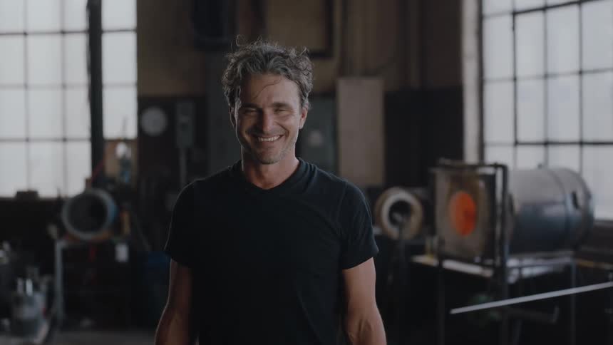 A portrait of a man indoors in glass blowing studio