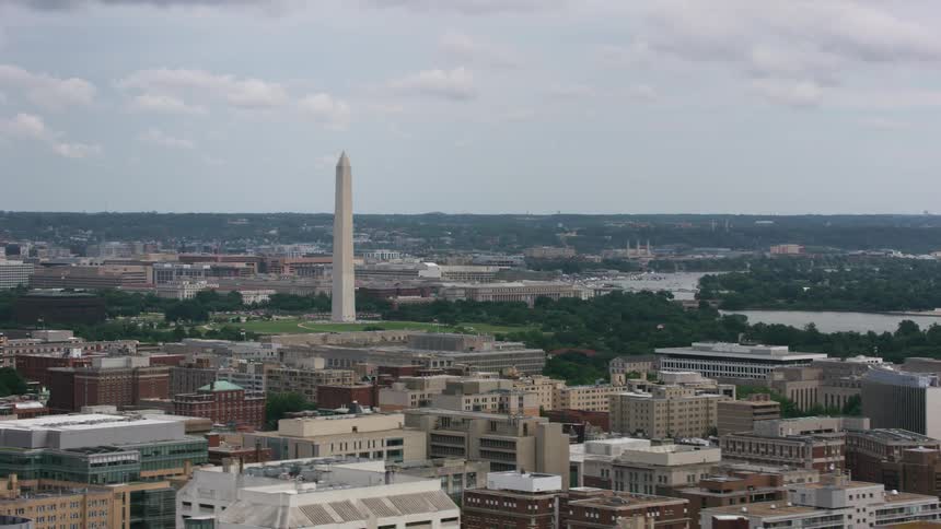 An aerial view of high rise apartment buildings surrounding a landmark by a river in a city
