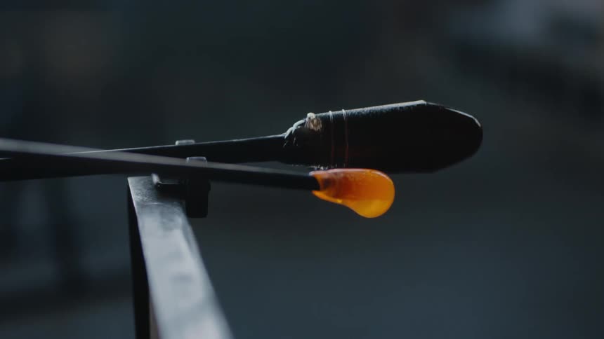 An artist rolling molten glass