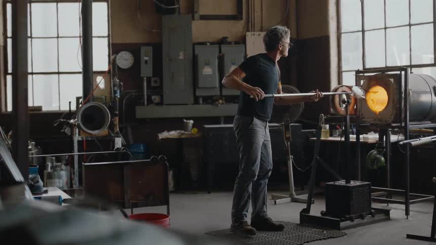 Artisan forming glass in a kiln in industrial art studio